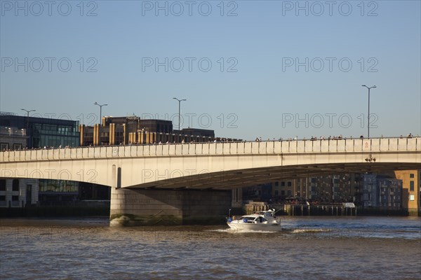 England, London, Southwark southbank early morning commuters crossing London Bridge to get to the City Financial District with moto cruiser passing underneath. Photo : Stephen Rafferty