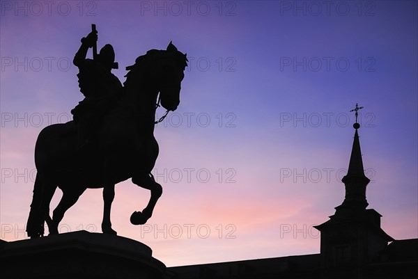 Spain, Madrid, Statue of King Philip II in Plaza Mayor silhouetted against evening sky. 
Photo Hugh Rooney / Eye Ubiquitous