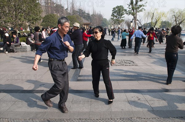 China, Jiangsu, Nanjing, Retired couples dancing beneath the Ming city wall at Xuanwu Lake Park Couple in foreground swinging arms in modern dance. 
Photo Trevor Page / Eye Ubiquitous