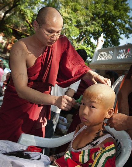 Thailand, Chiang Mai, Shaving of hair is part of the ritual of Poi Sang Long. This is the ordination ceremony for Shan boys to become novice Buddhist monks in Thailand. It is expected that every male will ordain as a monk at least once in his life. The entire ceremony last 3-4 days and relates directly to the life story of the Buddha who was once a prince in northern India and rejected his privileged royal lifestyle in favour of a humble existence seeking only inner enlightenment. After their heads are shaved the boys become crystal sons dressed only in white. This is followed by a period of 3 days when they dress elaborately and lavishly like the princes of old India. During that time they are pandered and catered to in the style of a prince. They are even carried about on the shoulders of family or friends so that their feet do not touch the ground. 
Photo Martin F. Johnston / Eye Ubiquitous