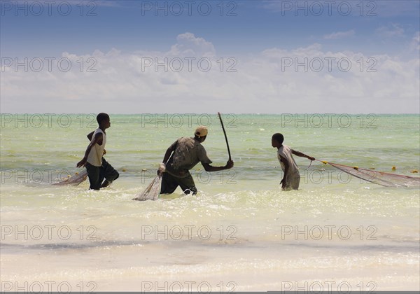 Tanzania, Zanzibar, Paje, Fisherman in the shallow waters off the beach pulling in their net. 
Photo Nic I Anson / Eye Ubiquitous