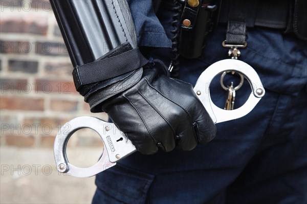 Law & Order, Crime, Police, Detail of Police officer wearing body armour and holding Hand Cuffs. 
Photo Sean Aidan