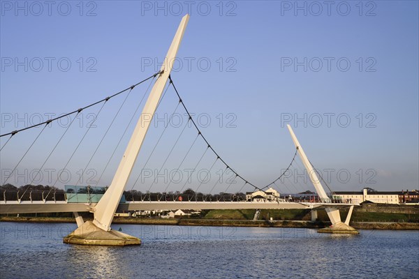 Ireland, North, Derry, The Peace Bridge over the River Foyle opened in 2011 with the former Ebrington Barracks in the background. 
Photo Hugh Rooney