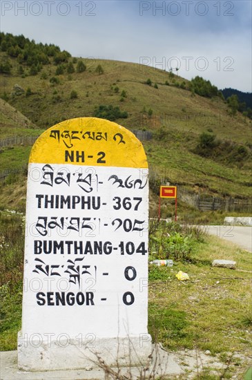 Bhutan, Sengor, Milestones on the side of the main east-west highway showing distances to towns. 
Photo Nic I'Anson