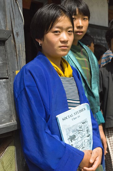 Bhutan, Mongar, Portrait of a Bhutanese school girl holding Social Studies textbook. 
Photo Nic I'Anson