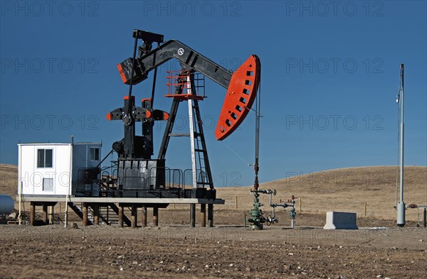 Canada, Alberta, Milk River Ridge , Oil pump jack or nodding donkey on the edge of the Baaken play  Flare tower at right.