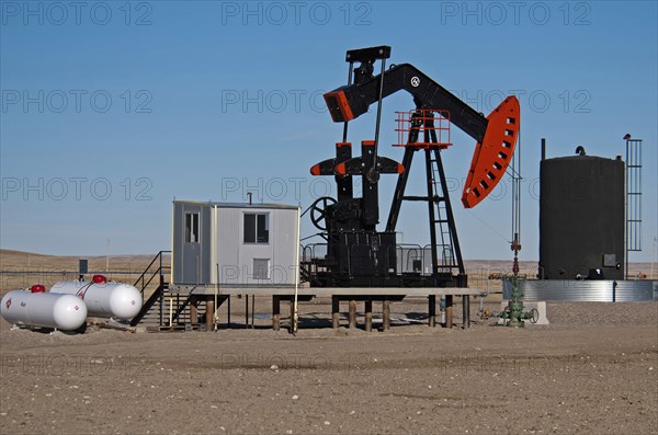 Canada, Alberta, Milk River Ridge, Oil pump jack or nodding donkey and storage tank on the edge of the Bakken Play near the Montana, USA border. 
Photo Trevor Page