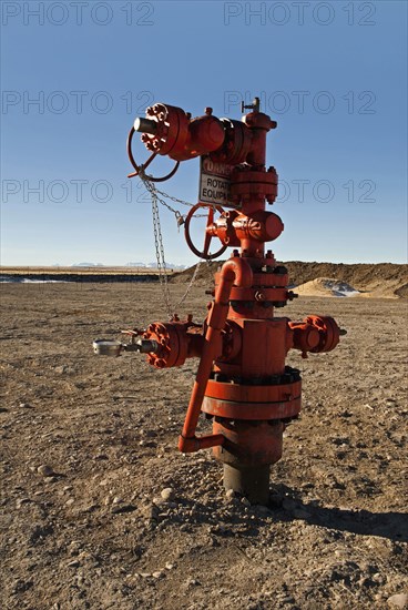Canada, Alberta, Del Bonita, Christmas tree atop a capped off oil well on the edge of the Bakken Play with line of the Rocky Mountains on the horizon. 
Photo Trevor Page