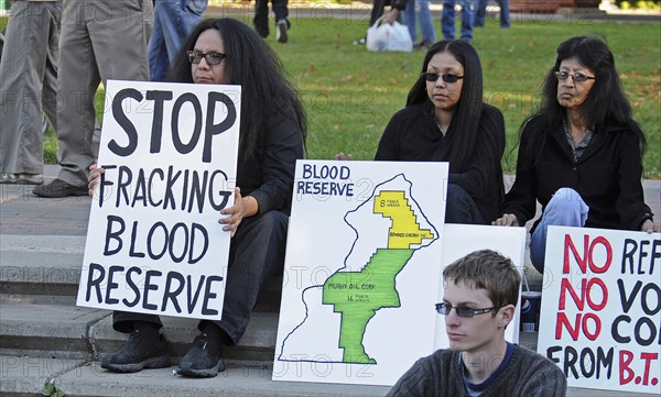 Canada, Alberta, Lethbridge, Three Blood Tribe members holding protest signs at anti-fracking demonstration. Map of Blood Reserve showing oil company concessions to Bowood Energy Ltd and Murphy Oil Corporation. The Blood or Kainai Indian Reserve is the largest aboriginal reserve in Canada. . 
Photo Trevor Page