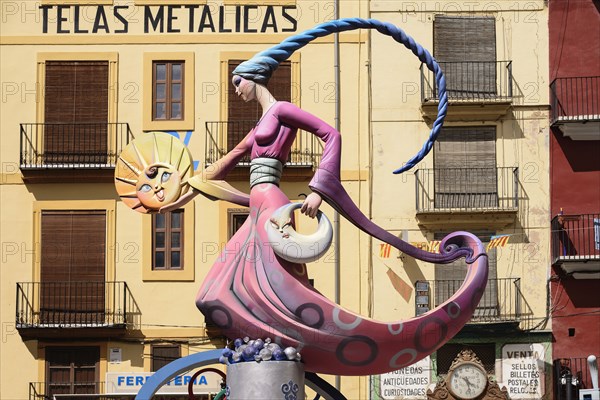 Spain, Valencia Province, Valencia, Papier Mache figure of a lady in a pink dress holding a replica of the sun during Las Fallas festival. 
Photo Hugh Rooney