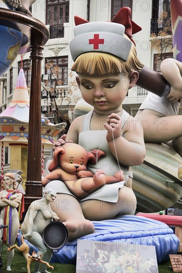 Spain, Valencia Province, Valencia, Papier Mache figure of young girl in nurses outfit with teddy bear in the street during Las Fallas festival. 
Photo Hugh Rooney