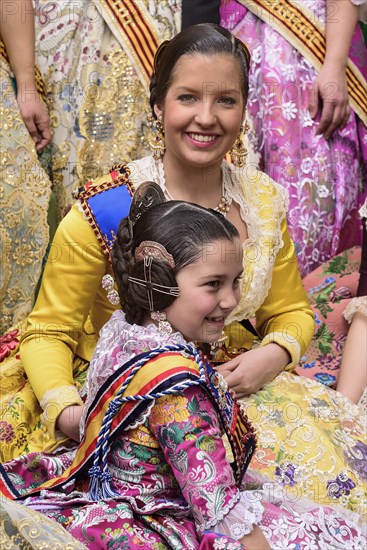 Spain, Valencia Province, Valencia, Reina Fallera in traditional Valencian costume taking a break with young child also in traditional Valencian costume during Las Fallas festival. 
Photo Hugh Rooney