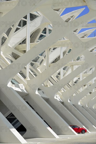 Spain, Valencia Province, Valencia, Spain, Valencia Province, Valencia, La Ciudad de las Artes y las Ciencias, City of Arts and Sciences, Principe Felipe Science Museum, Detail of the building with red Mercedes car protruding from one of the arches. 
Photo Hugh Rooney