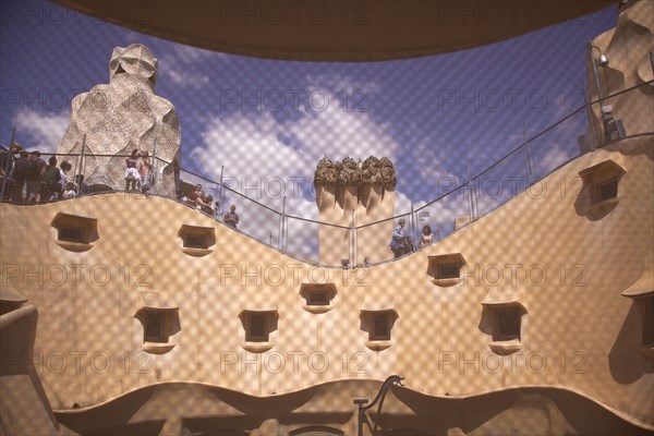 Spain, Catalonia, Barcelona, La Pedrera or Casa Mila on Passeig de Gracia, designed by Antoni Gaudi, view of the roof through mesh covered attic window. 
Photo Stephen Rafferty