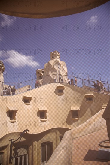 Spain, Catalonia, Barcelona, La Pedrera or Casa Mila on Passeig de Gracia, designed by Antoni Gaudi, view of the roof through mesh covered attic window. 
Photo Stephen Rafferty