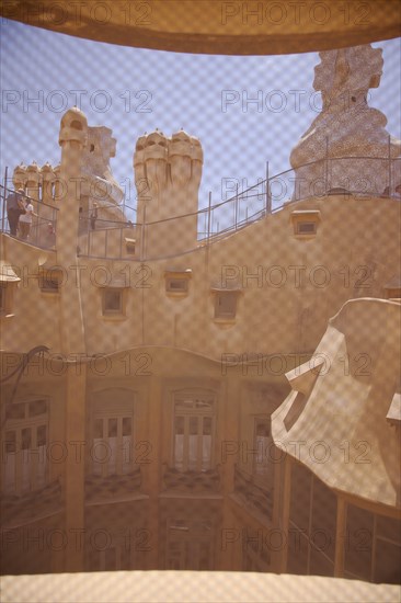 Spain, Catalonia, Barcelona, La Pedrera or Casa Mila on Passeig de Gracia, designed by Antoni Gaudi, view of the roof through mesh covered attic window. 
Photo Stephen Rafferty