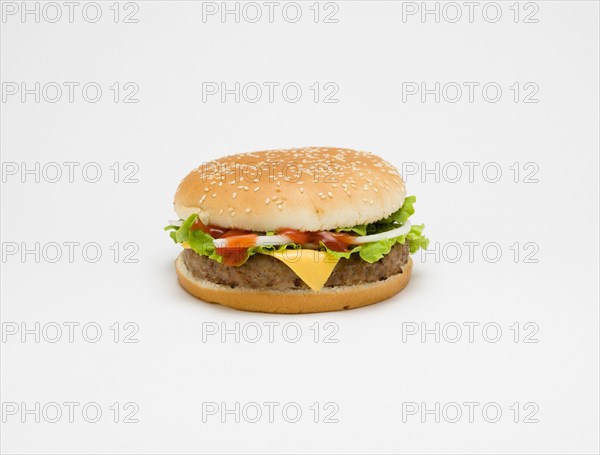 Food, Cooked, Meat, Single cheesburger with salad and tomato ketchup in a bun on a white background.