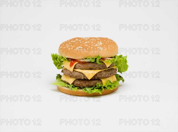 Food, Cooked, Meat Triple cheesburger with salad and tomato ketchup in a bun on a white background.