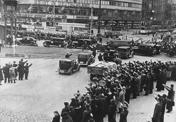 A Berlin, les passants saluent le Führer dont ils entendent la voix sur la T.S.F. (1933)