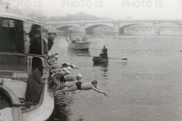 A series of swimmers is diving from a boat