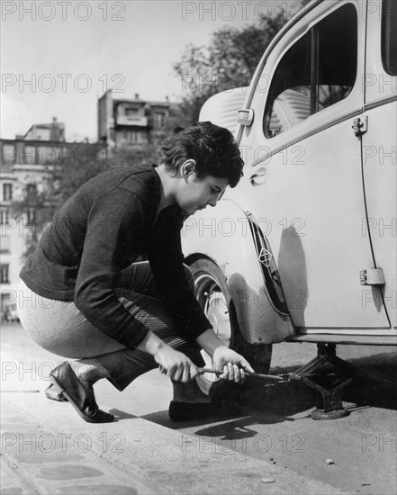 Femme changeant la roue de sa voiture